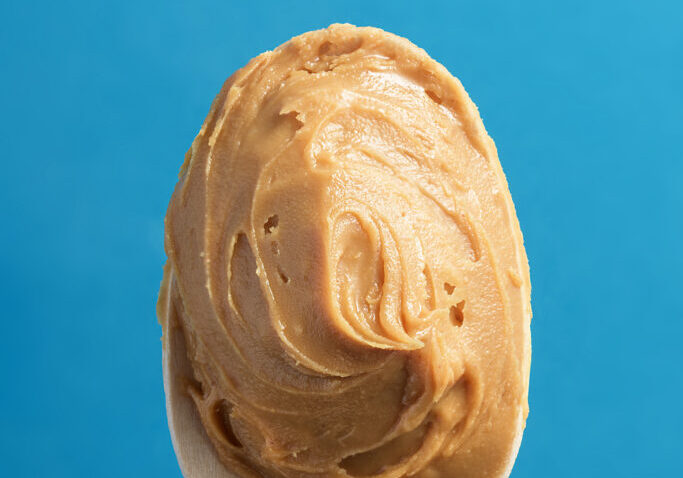 Spoon of nut oil on a blue background. Spoon of nut oil on a blue background.